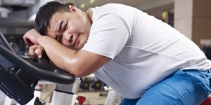 an overweight young man exhausted with exercising in fitness center.